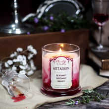 Load image into Gallery viewer, A lit white soy candle with swirls of blood red wax spreading through it. Label reads "Astarion, Bergamot, Rosemary, Brandy. Baldur's Gate 3 Inspired Candle"