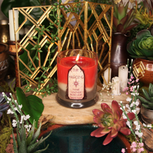 Load image into Gallery viewer, A candle with red wax on top, transitioning to cream and brown layers, set in a clear glass jar. The label reads 'Harding’s Blend'.