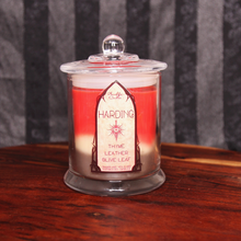Load image into Gallery viewer, A red candle labeled 'Harding's Blend' with layers of white and brown wax, sitting on a wooden surface.