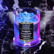 Load image into Gallery viewer, Pink, black and blue candle labeled 'Jinx' with a blue wax rose on top.
