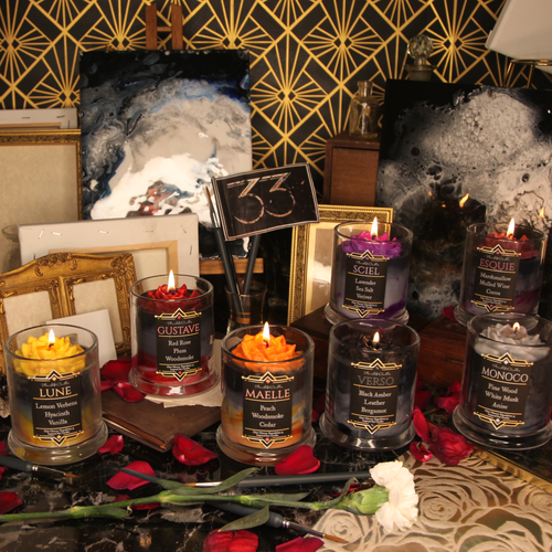 A full set of our seven Clair Obscur: Expedition 33 inspired soy candles all burning together in one art deco themed scene.