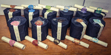 Load image into Gallery viewer, 11  packaged custom candles wrapped in black paper with matching wax seals and care scrolls. 
