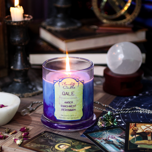 A lit blue soy candle with swirls of purple wax spreading through it. Label reads 