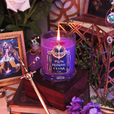 Purple candle with a label on a wooden surface surrounded by decorative items