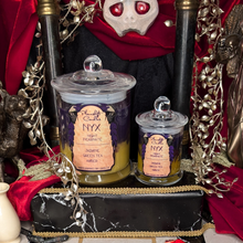 Load image into Gallery viewer, Large and Small Nyx candles in purple and gold wax poured in clear glass jars with lids.
