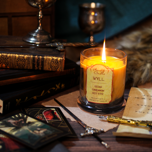 A lit orange-yellow soy candle with swirls of black wax spreading through it. Label reads 